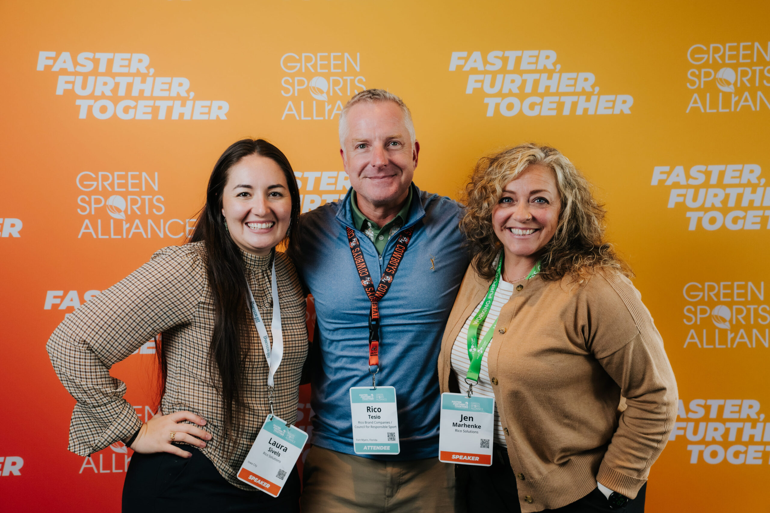 Green Sports Alliance Summit attendees posing in front of the 'Faster, Further, Together' event backdrop.