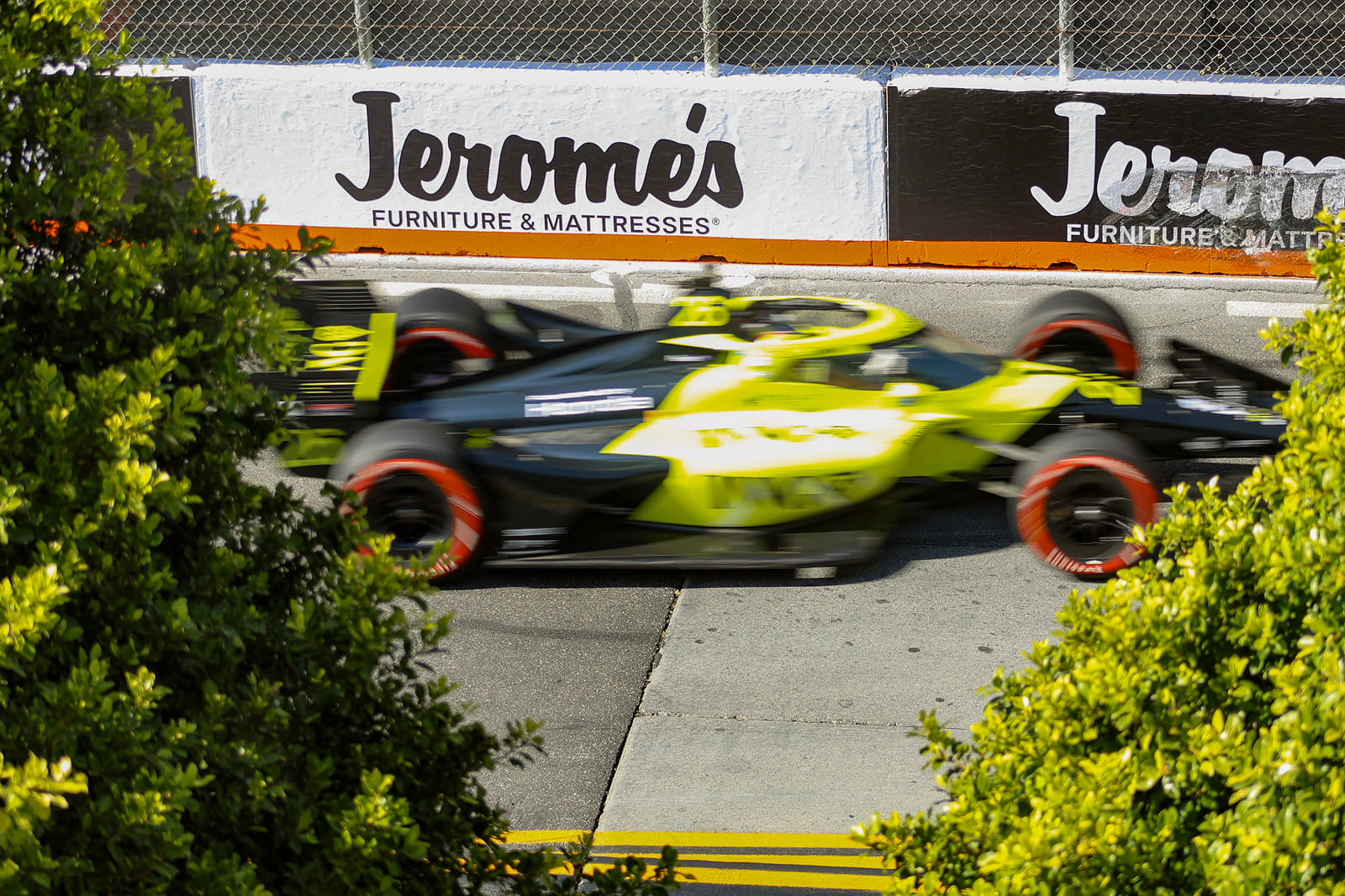 Race car passing custom sponsor signage installed throughout the Acura Grand Prix of Long Beach circuit.