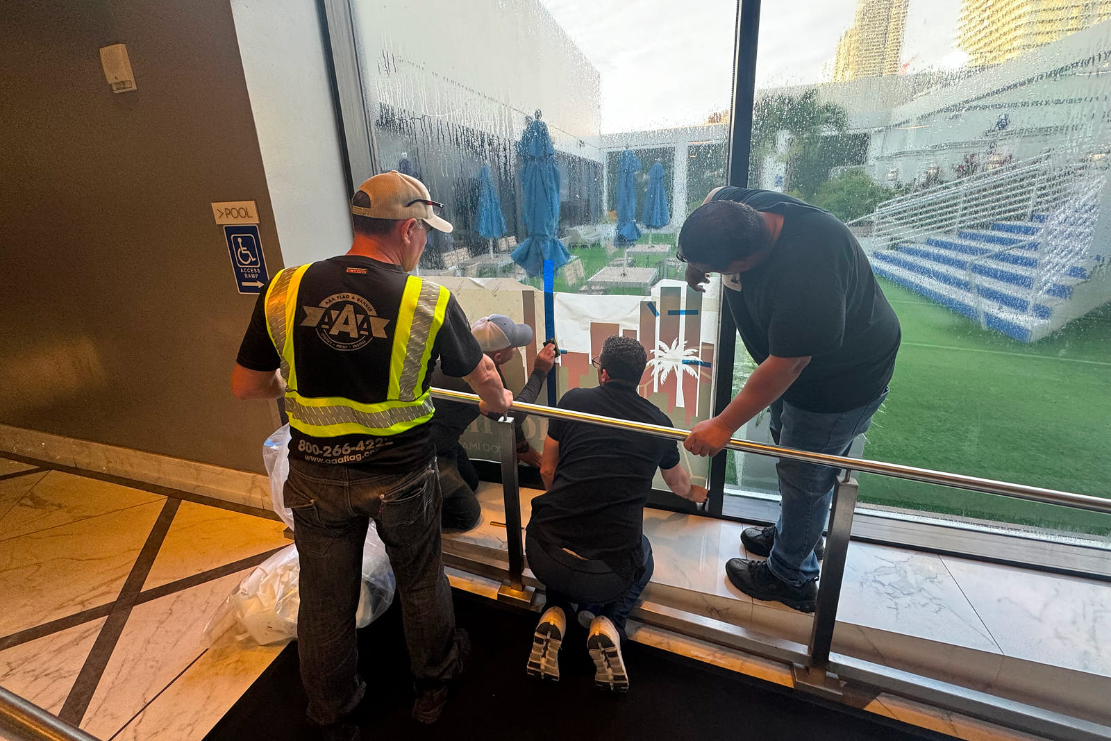 A3 Visual installation team applying custom window graphics at Hilton Miami Downtown for the Match Day Stay Host City Experience.