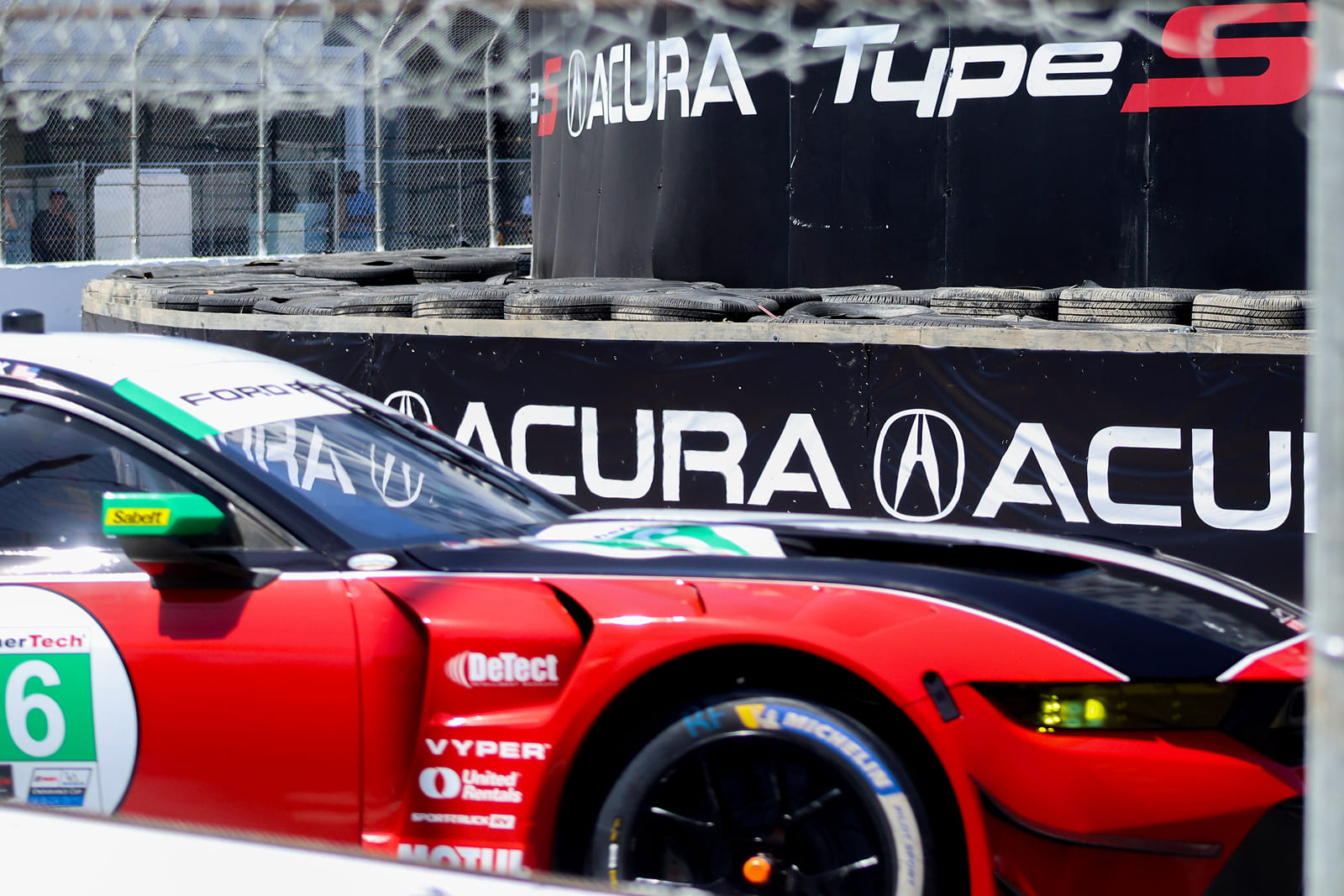 Race car competing alongside custom Acura-branded track wall graphics produced by A3 Visual.
