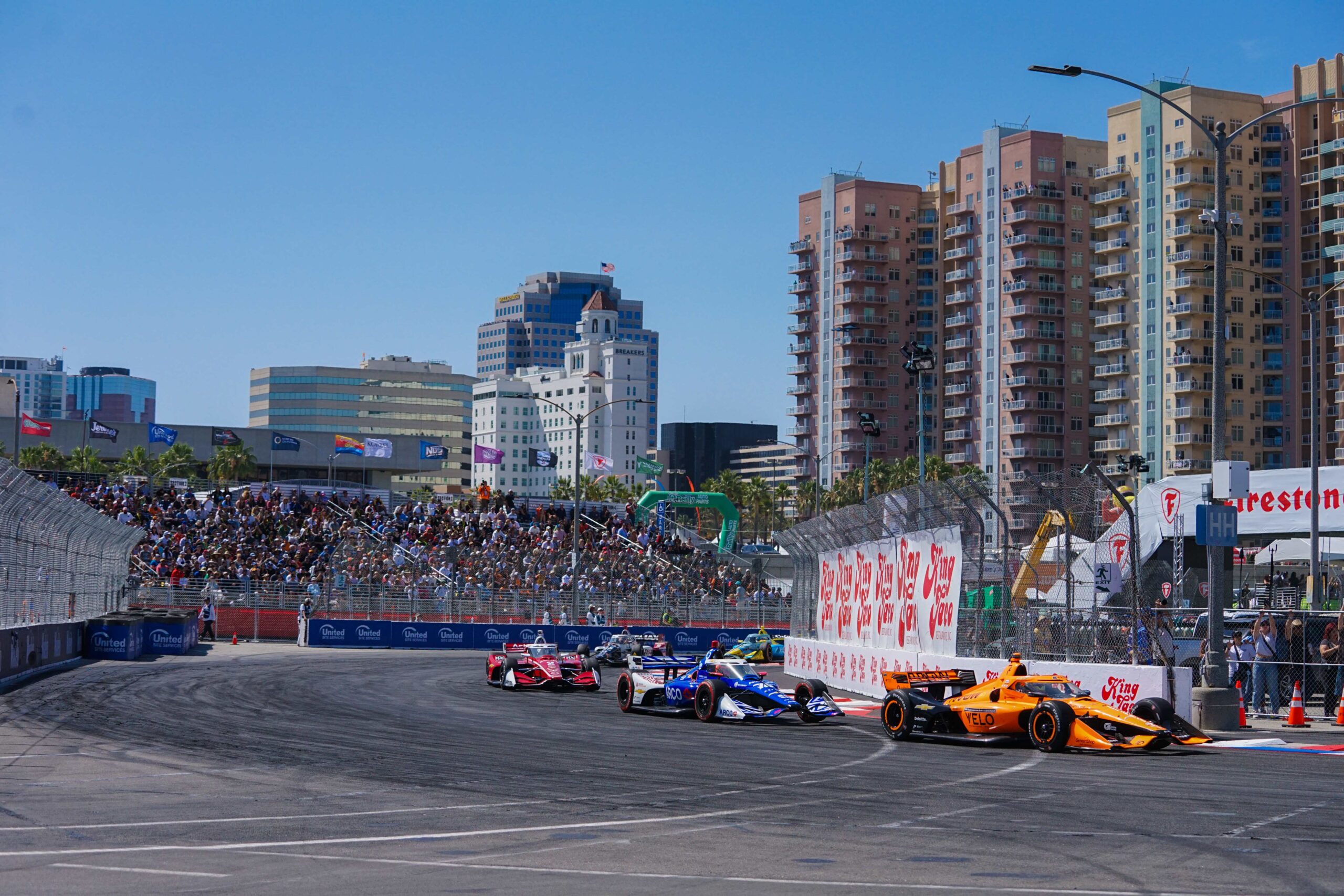 INDYCAR race cars compete during the 2026 Acura Grand Prix of Long Beach, surrounded by large-format trackside graphics, sponsor branding, and event signage produced and installed by A3 Visual.